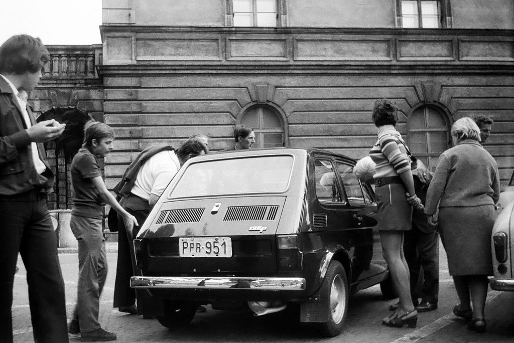 Fiat 126p oglądany na ulicy przez przechodniów, auto na próbnych blachach