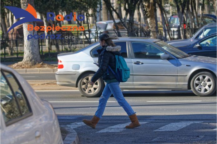 Młoda kobieta na przejściu dla pieszych w mieście. Pieszy - prawa i obowiązki.