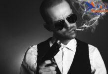 Na zdjęciu mężczyzna w typie włoskiego mafioso, z papierosem w ustach i bronią w ręce. Pospolity bandytyzm.