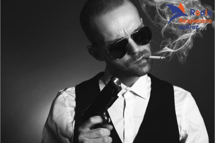 Na zdjęciu mężczyzna w typie włoskiego mafioso, z papierosem w ustach i bronią w ręce. Pospolity bandytyzm.