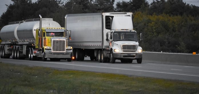 Międzynarodowy Dzień Kierowcy Zawodowego. Na fotografii widać jadące drogą wielopasmową dwa samochody ciężarowe, jeden z nich to cysterna.