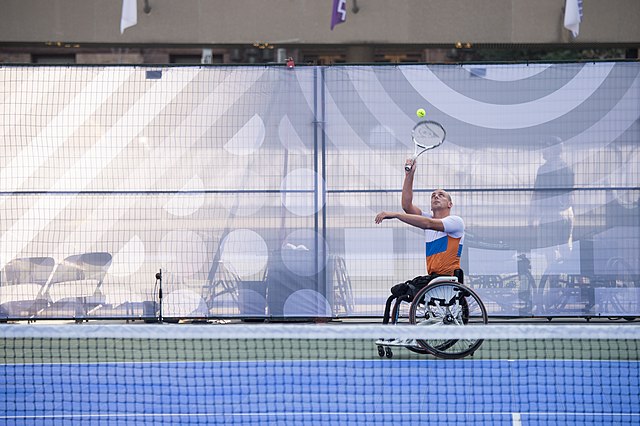 Na zdjęciu zawodnik na wózku z Holandii serwujący podczas meczu. Tenis ziemny na wózkach.