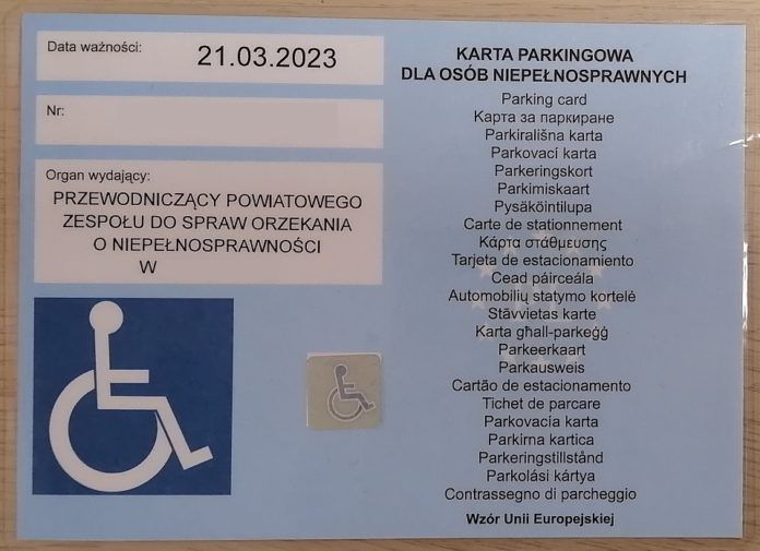Karta parkingowa dla osób niepełnosprawnych. Dokument po lewej zawiera datę ważności, numer oraz nazwę organu wydającego. Po lewej na dole granatowy symbol osoby niepełnosprawnej oraz hologram. Prawa strona blankietu zawiera napis karta parkingowa w 24 językach unii europejskiej.