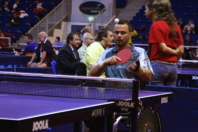 Na zdjęciu mężczyzna na wózku inwalidzkim grający w tenisa stołowego.