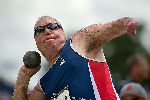 Na zdjęciu niepełnosprawny zawodnik pchający kulą.