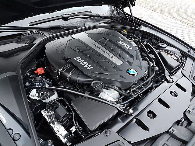 Najgorsze silniki benzynowe BMW. Zbliżenie komory silnika z jednostką N63. Prawie cała przestrzeń jest przesłonięta plastikową obudową silnika. Widoczne logo BMW oraz napis Twin Power Turbo oraz BMW.