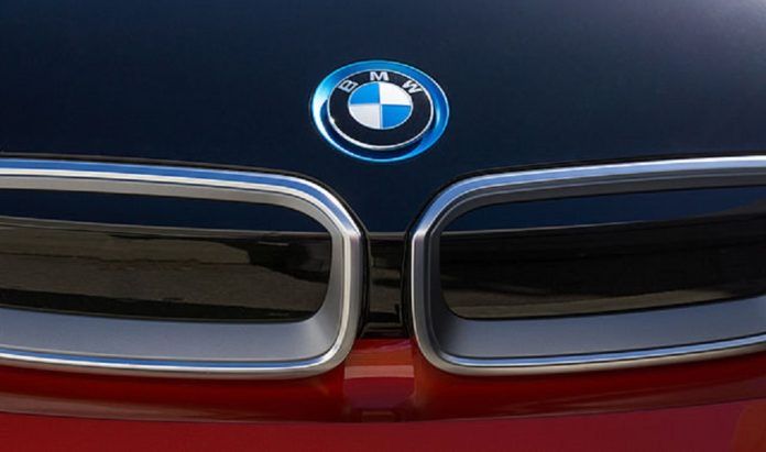 Najgorsze wysokoprężne silniki BMW. Duże zbliżenie na przód BMW i3. Widoczne są nerki oraz emblemat marki. Maska granatowa dół samochodu bordowy.