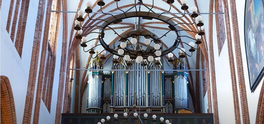 Sezon muzyki organowej 2022 otwarty. Na fotografii wnętrze katedry w koszalinie, w centrum widoczne organy lekko przysłonięte przez żyrandole.
