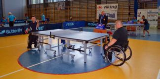 Na zdjęciu niepełnosprawni na wózkach inwalidzkich podczas meczu w tenis stołowy. Do artykułu. Tenis stołowy dla osób niepełnosprawnych.