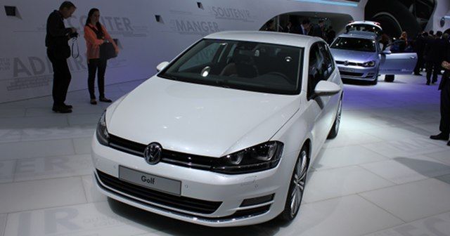 Nowy silnik benzynowy Volkswagena. Na zdjęciu salon samochodowy i prezentacja samochodów Volkswagen Golf MK7. Ściany i podłoga białe, samochody ustawione gęsiego, wszystkie też białe. Wokół zgromadzeni gośfcie salonu.