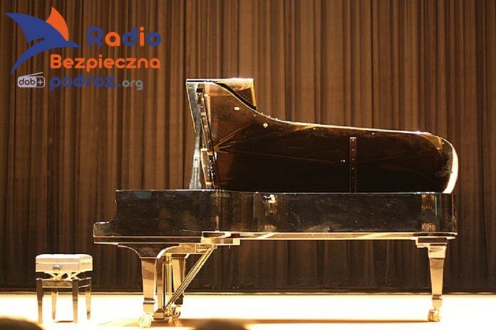 XXVIII Komeda Jazz Festival. Na pustej scenie stoi fortepian wraz ze stołkiem. Widok z profilu, na tle brązowej, pofalowanej kotary.