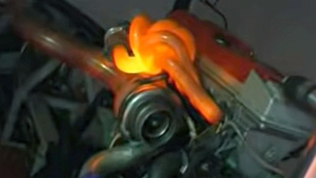 Turbosprężarka co to jest. Na cieno szarym tle leży nowiutka srebrzyście lśniąca turbosprężarka. Jej kształt przypomina spiralnie zwiniętą rurę o średnicy około 5 centymetrów.