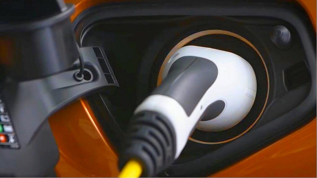 Dopłaty do samochodów elektrycznych - Wtyczka i kabel tkwiące w gnieździe ładowania samochodu elektrycznego