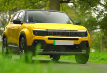 Jeep Avenger - żółto-złocisty Jeep, zaparkowany w pobliżu drzew, częściowo jego podwozie jest zasłaniane przez trawy