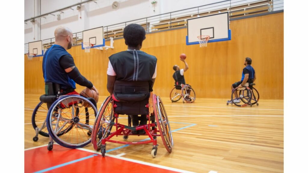Czym jest System IPFRON+? Mężczyźni na wózkach inwalidzkich grający na hali sportowej w koszykówkę