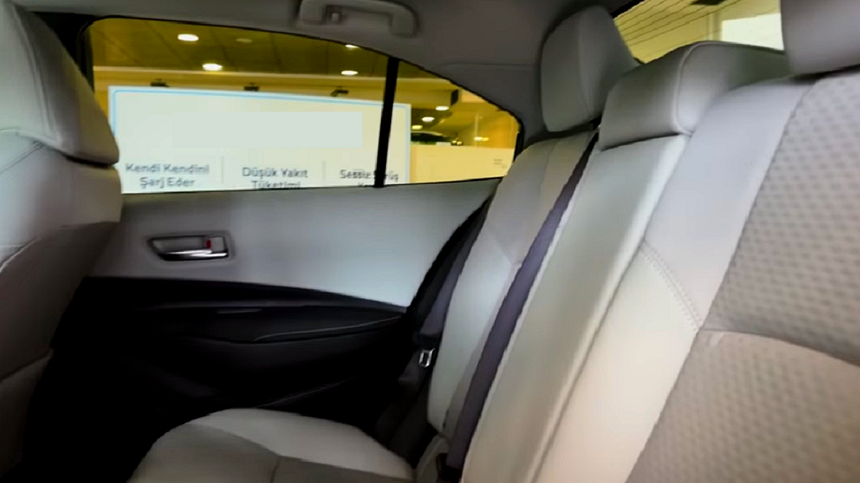 Toyota Corolla 1.8 Hybrid - widok na tylną kanapę z jasno-beżową tapicerką, delikatnie pikowaną w romby.