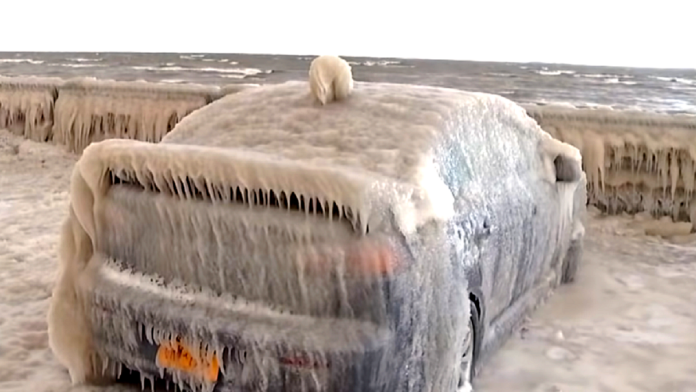 Zamarznięte szyby w samochodzie - samochód zaparkowany blisko brzegu oceanu jest całkowicie pokryty kilkunastocentymetrową warstwą lodu z rozbryzgów fal