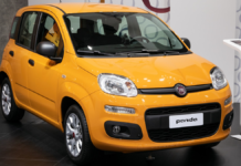 Fiat Panda - nowiutki Fiat Panda Hybrid prezentowany w salonie, na tle białej ściany stoi mocno żółty, lśniący samochodzik.