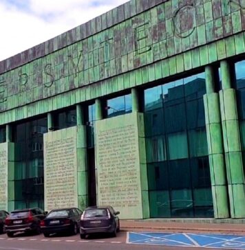 Biblioteka Uniwersytetu Warszawskiego - widok frontowego wejścia do gmachu. Lekko wklęsła półkoliście fasada z dużą ilością szkła. Całość pokryta zieloną patyną.