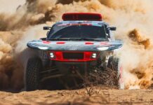 Carlos Sainz - Dakar 2024, na zdjęciu kosmicznie wyglądający samochód w tumanach kurzu i piasku.