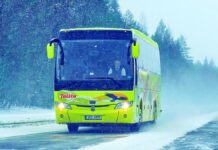 Kontrola autokaru - po zaśnieżonej drodze w Finlandii, jedzie cytrynowy autobus pokryty kolorowymi grafikami i napisami, lekko prószy śnieg.