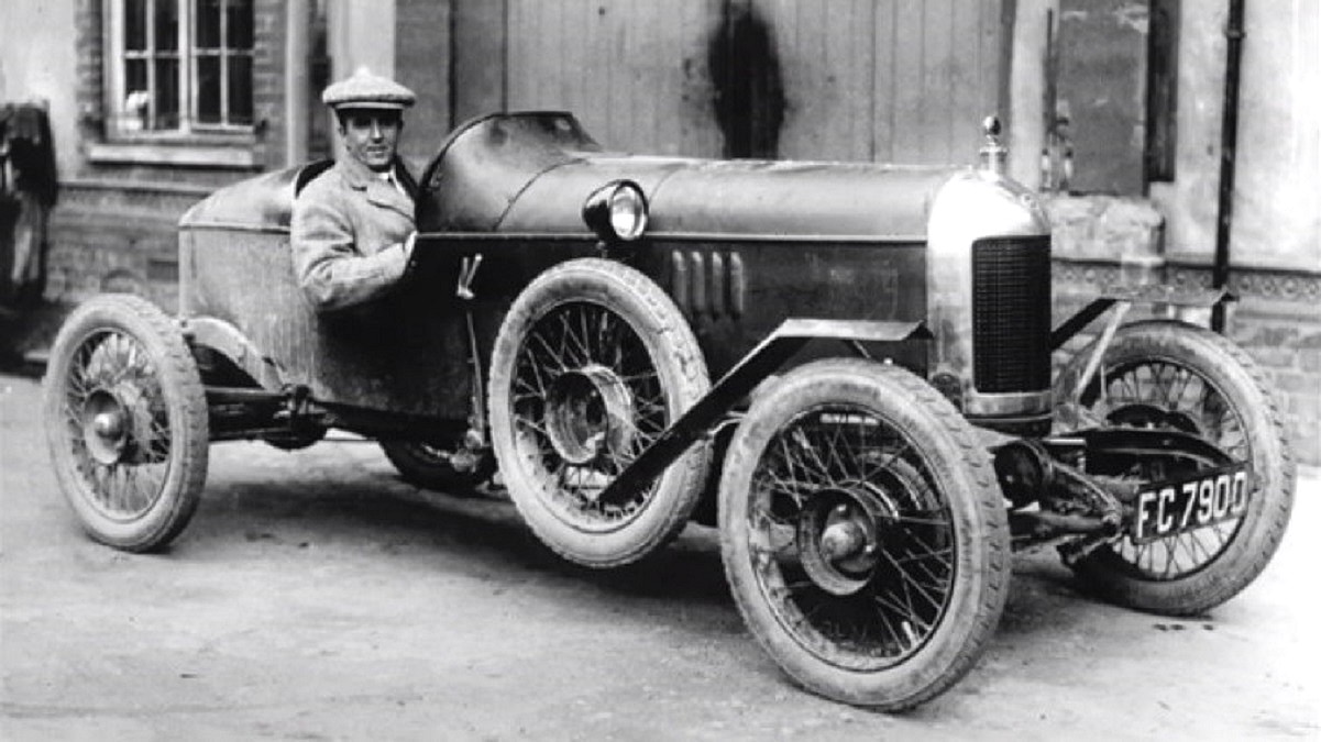 MG Motor - na czarno-białym zdjęciu z około 1925 roku, w wyścigowym MG siedzi kierowca w marynarce i kaszkiecie na głowie.