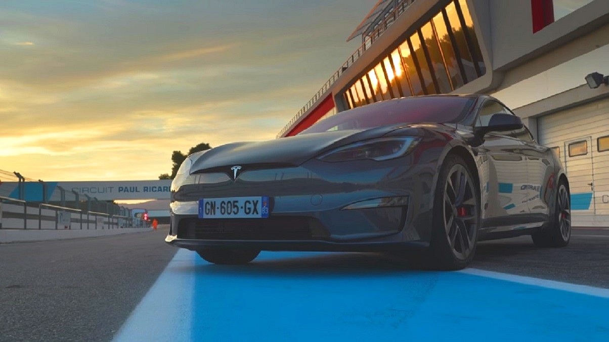 Porsche Taycan - ciemno-szara Tesla o zachodzie słońca, zaparkowana na torze wyścigowym