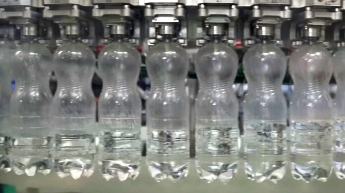 Koniec z pseudo-EKO - linia rozlewnicza w wytwórni wody mineralnej. Butelki PET, przesuwają się jedna za drugą, niekończącym się szeregiem.