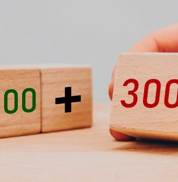 Wyższa kwota świadczenia 500+ - dłoń ustawia obok siebie trzy drewniane klocki. Na pierwszym jest liczba 500, na drugim znak plus a na trzecim dopiero dostawianym jest liczba 300