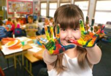 zmiany w szkołach w 2024 roku, dziewczynka w klasie pokazuje dłonie umazane kolorowymi farbkami