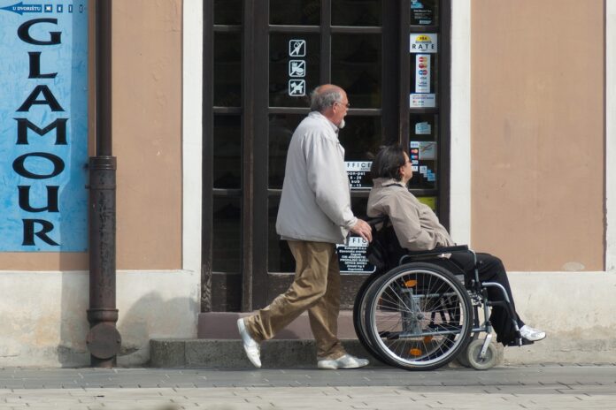 Aktywny Samorząd 2024, mężczyzna wiezie kobietę na wózku inwalidzkim