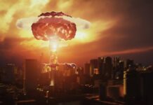 atak nuklearny - apokaliptyczny obraz eksplozji nuklearnej nad miastem. Ognisty grzyb atomowy oświetla jeszcze stojące budynki na płomieniście pomarańczowo.