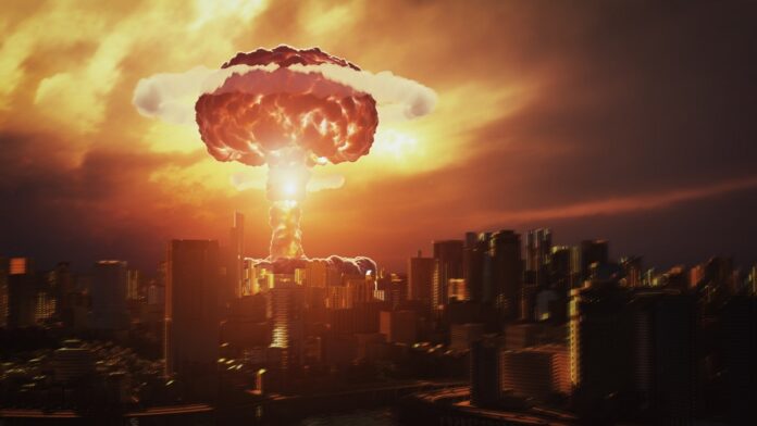 atak nuklearny - apokaliptyczny obraz eksplozji nuklearnej nad miastem. Ognisty grzyb atomowy oświetla jeszcze stojące budynki na płomieniście pomarańczowo.