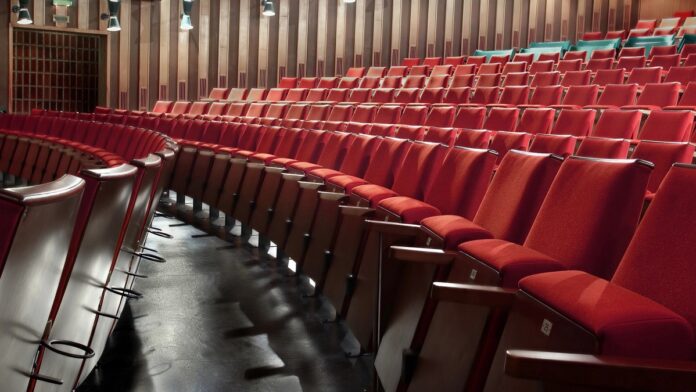 bilety dla niepełnosprawnych, pusta widownia kina z rzędami miękkich, czerwonych foteli