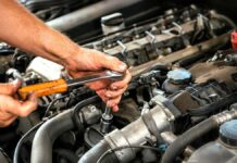 Dobry i uczciwy mechanik to prawdziwy skarb uczciwy mechanik - zbliżenie na brudne od smaru dłonie mechanika. Trzymanym kluczem dokręca jakąś śrubę w komorze silnika.