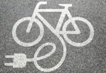 Angielski rząd oszalał - na szarym asfalcie namalowany białą farbą symbol roweru z przewodem i wtyczką.
