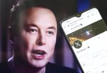 Elon Musk - zbliżenie na ekran smartfona z wyświetlonym profilem Elona Muska. W tle lekko rozmyty portret Elona.