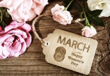 Międzynarodowy Dzień Kobiet - na starym drewnianym blacie stołu, leży pęk różowych róż, oraz stylizowany bilecik z napisem po angielsku 8 marca, międzynarodowy dzień kobiet.
