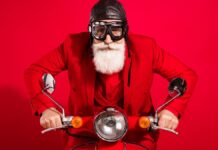 Nowelizacja unijnego prawa jazdy - wyluzowany Święty Mikołaj ubrany w czerwony garnitur, ma na głowie skórzaną pilotkę i gogle. Jedzie na czerwonym skuterze, ma poważną twarz i długą białą brodę. Czerwone tło.