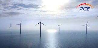 PGE Polska Grupa Energetyczna - na morzu stoi grupa wiatraków, elektrowni wiatrowej. Pogodny słoneczny dzień, białe wiatraki na tle błękitu morza i nieba.
