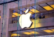 Firma Apple - Na przezroczystej, szklanej elewacji domu towarowego widać ogromne, biało-podświetlone logo firmy. Ugryzione jabłko. alphabet oraz apple i meta na celowniku KE