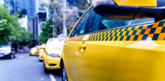 firma Uber - na ulicy Melbourne, stoi sznur żółtych taksówek z charakterystycznymi pasami, czarno-żółtych szachownic wzdłuż całego samochodu.