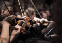program Festiwalu Muzyki Filmowej, muzycy grają na skrzypcach w sali koncertowej