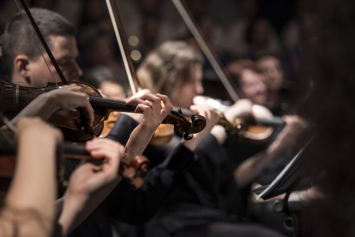 program Festiwalu Muzyki Filmowej, muzycy grają na skrzypcach w sali koncertowej