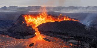 stan wyjątkowy - widok na krater islandzkiego wulkanu z którego wypływa gorąca, rozgrzana do czerwoności lawa.