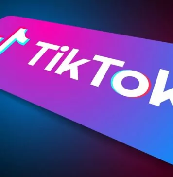 Ciąg dalszy problemów TikToka - komputerowe wyobrażenie leżącego smartfona. Na fioletowo-niebieskim ekranie znajduje się duże, białe logo TikToka.