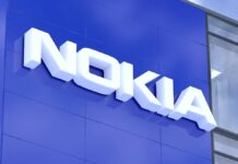 Nokia zwalnia pracowników - zbliżenie na biurowiec. Na niebieskiej fasadzie, wysoko pod dachem umieszczony jest biały napis NOKIA.