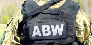 Szpiegował na rzecz Rosji - zbliżenie na plecu funkcjonariusza ABW w zielonym ubiorze maskującym. Na tyle czarnej kamizelki taktycznej, białe litery ABW.