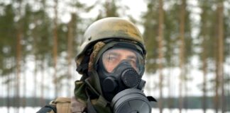 Chloropikryna w Ukrainie - zbliżenie na głowę żołnierza w pełnym rynsztunku. Na leśnym poligonie, ubrany w zielono-brązowy strój maskujący, ma założoną na twarz maskę przeciwgazową oraz hełm.
