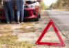 Rozładowany akumulator na trasie - trójkąt przy drodze i auto z podniesioną maską